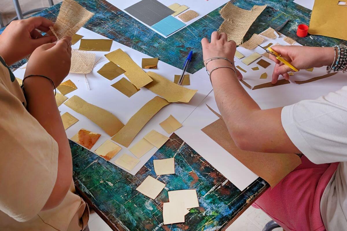 Le mani di due bambini che tagliano quadrati di carta in un laboratorio