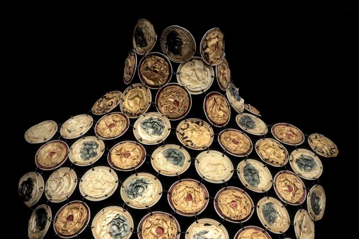 Foto di un dettaglio di abito fatto con capsule del caffè