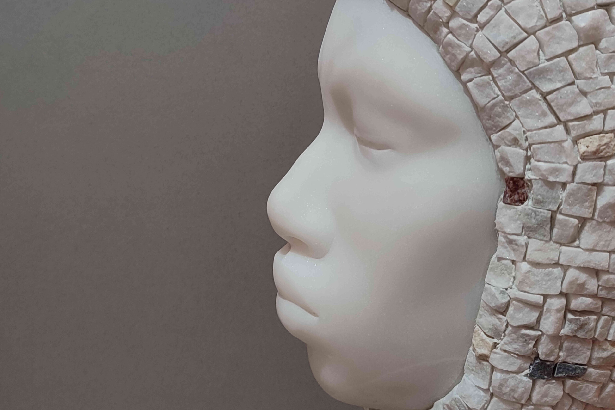 Foto di un dettaglio dell'opera con viso scolpito di profilo e mosaico