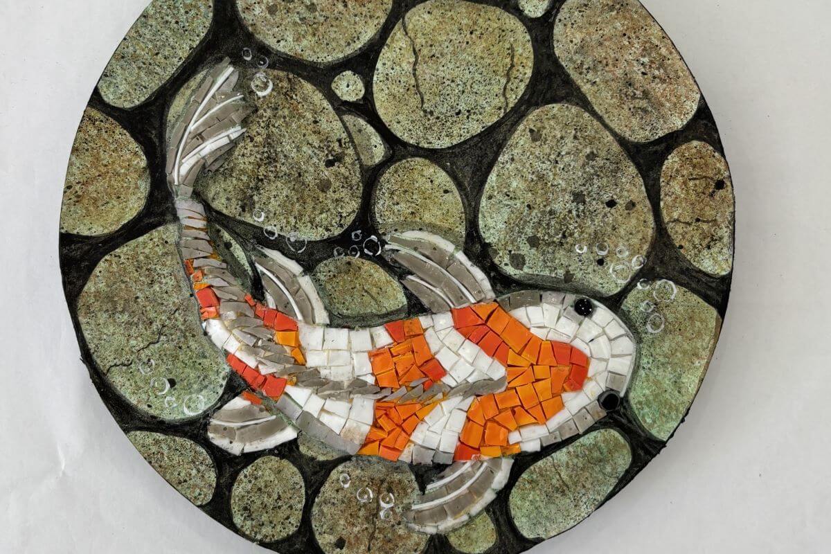 Foto di dettaglio di un mosaico su base rotonda con carpa koi.