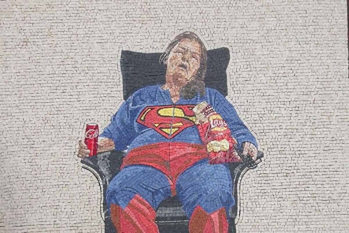 Foto di un mosaico con una signora addormentata in poltrona e vestita da Superman.