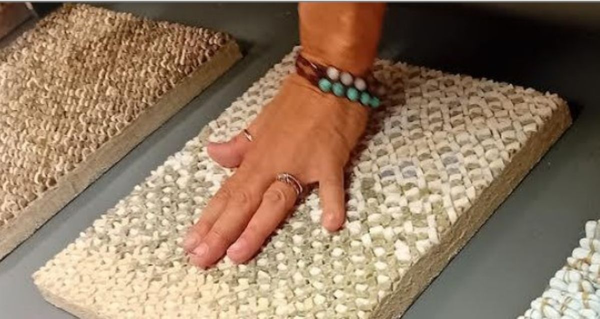 Foto di una mano che tocca un mosaico in tessere bianche e grigie