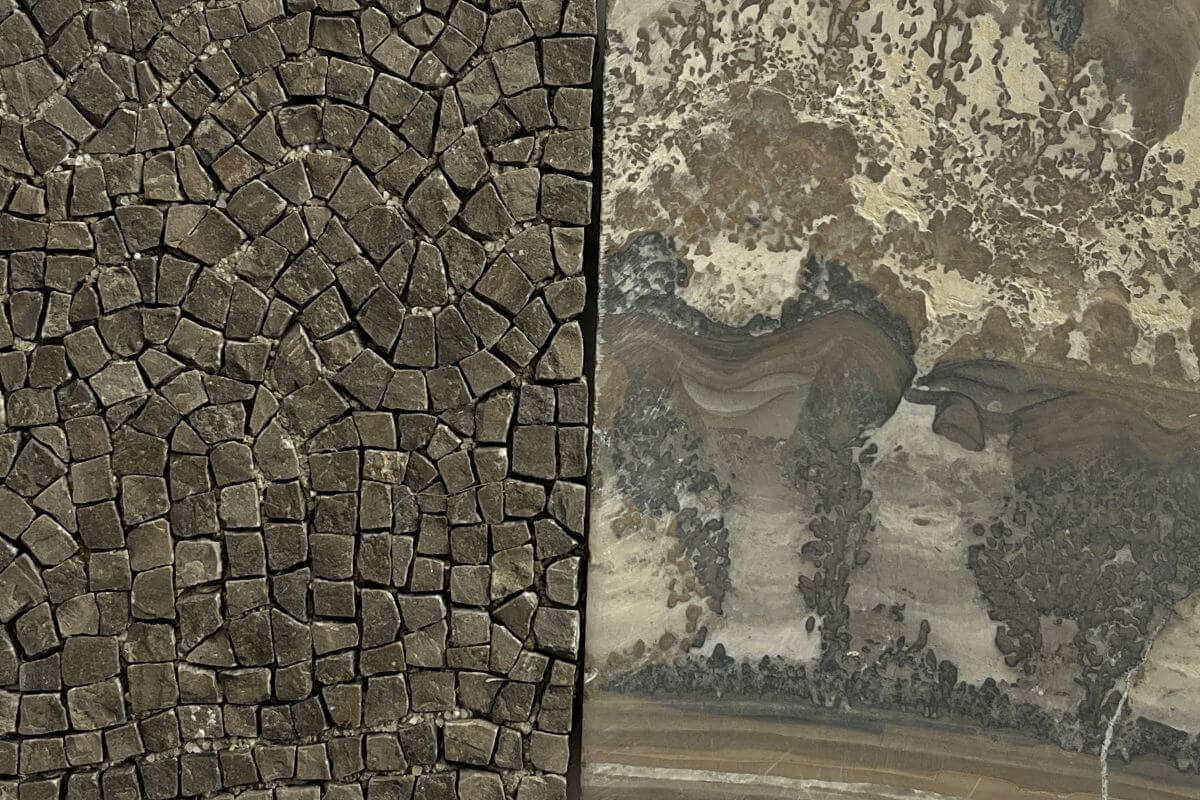 Foto di un'opera metà con tessere di mosaico marroni e metà in pietra.