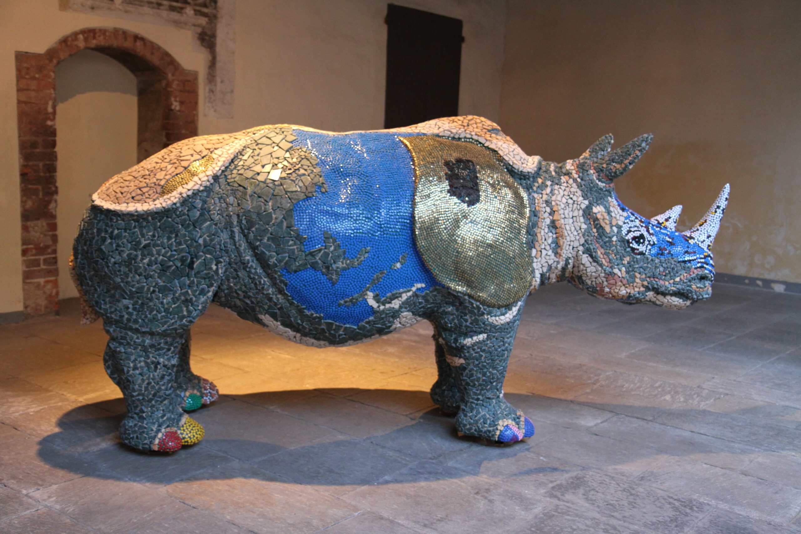 Foto di una scultura a forma di rinoceronte rivestito di mosaico.
