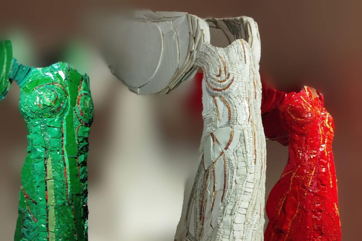 Foto di tre statue alate una verde, una bianca, una rossa.