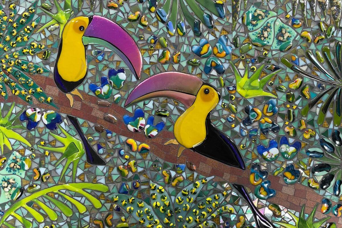 Foto di un mosaico di smalti colorati, con due tucani in primo piano.