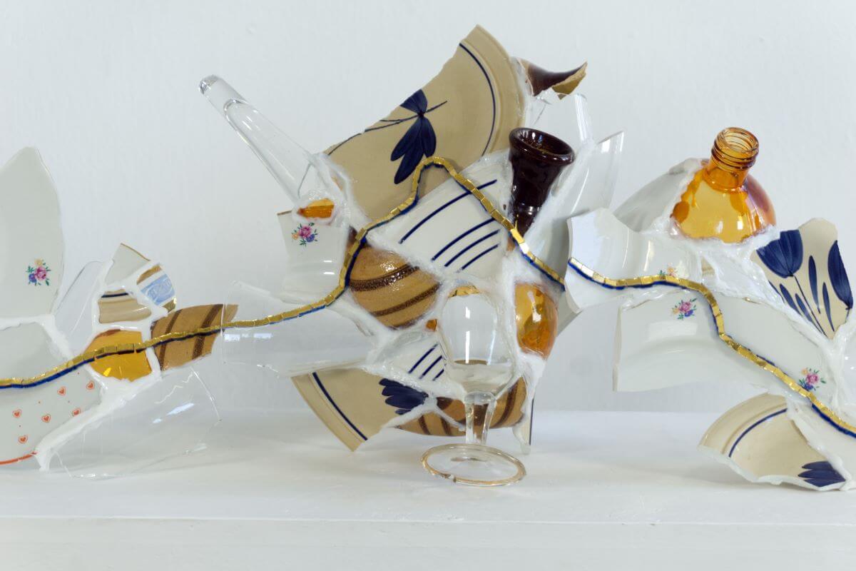 Foto di un'opera costituita da frammenti di ceramica unite da una linea di mosaico di tessere d'oro.