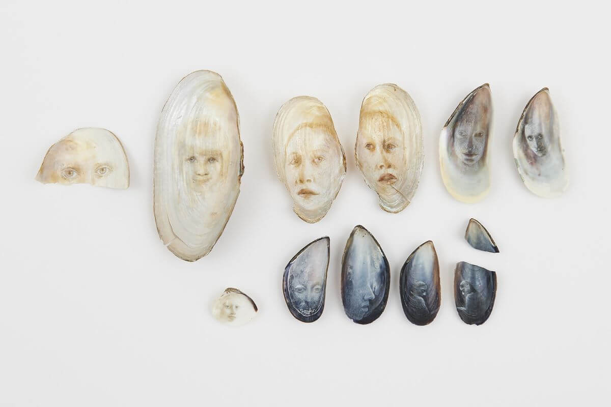 Foto di una serie di conchiglie su cui sono stati dipinti piccoli ritratti.