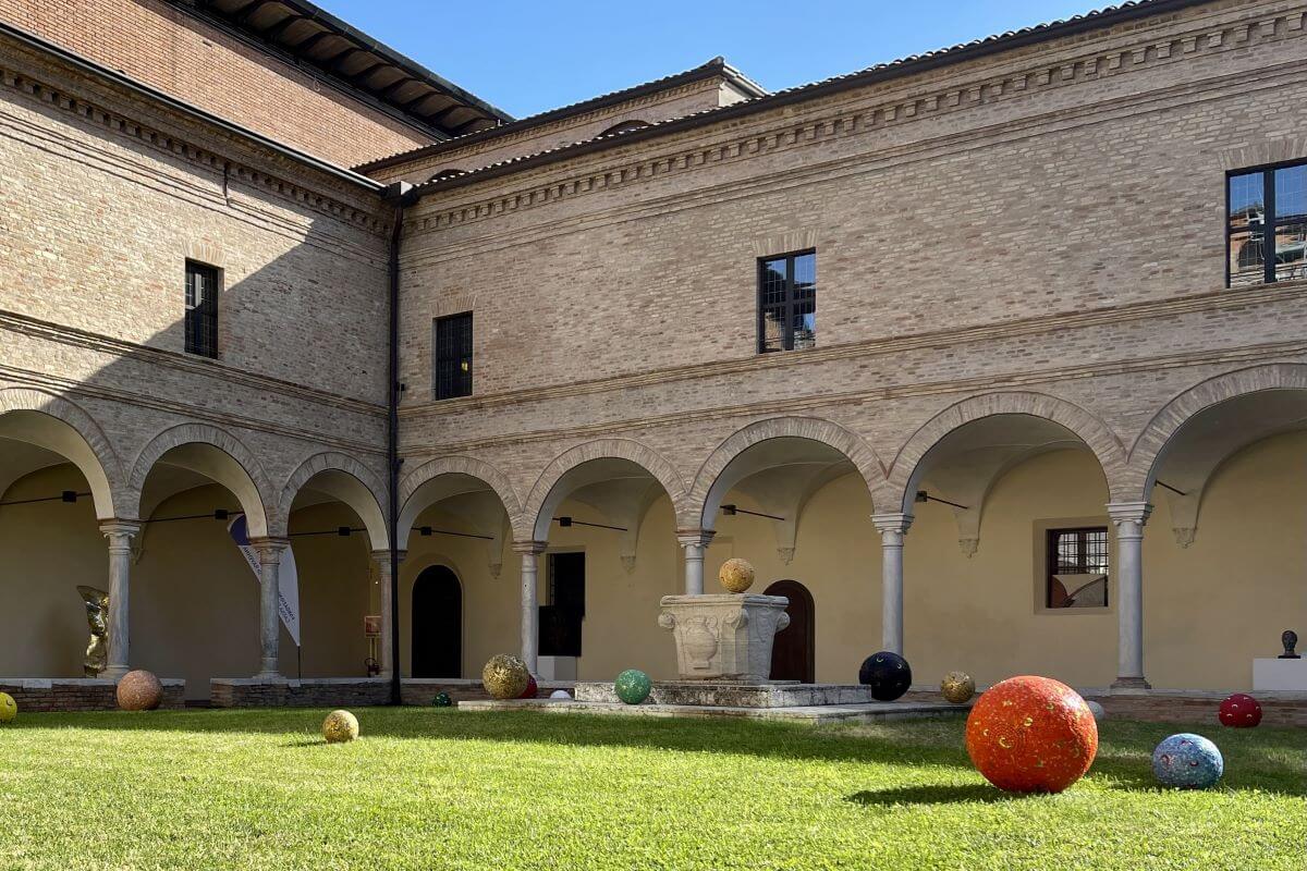 Foto del chiostro con le sfere mosaicate di Nittolo sull'erba del cortile e sul pozzo.