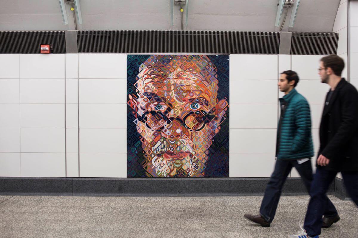 Foto di un corridio della metro con un'opera dipinta e due passanti.