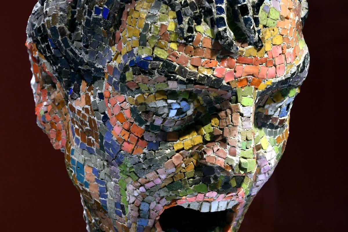 Foto di una scultura mosaicata che rappresenta la testa un uomo che grida