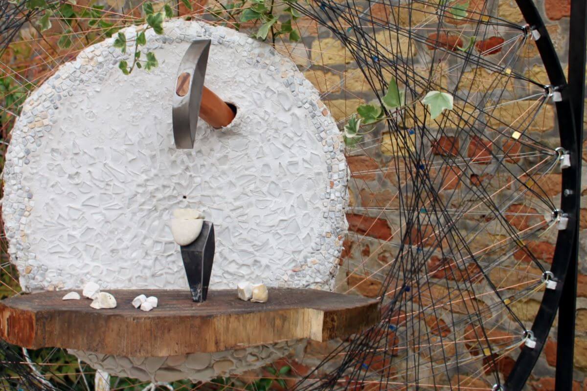 Foto di una martellina che spunta dal muro mosaicato in bianco